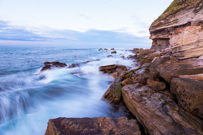 Scenic view of rocks in sea against sky