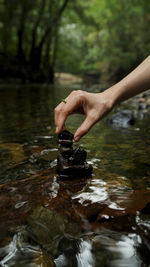 Hand stacking rocks on a small stream