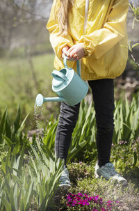 Little girl in a garden with green watering pot