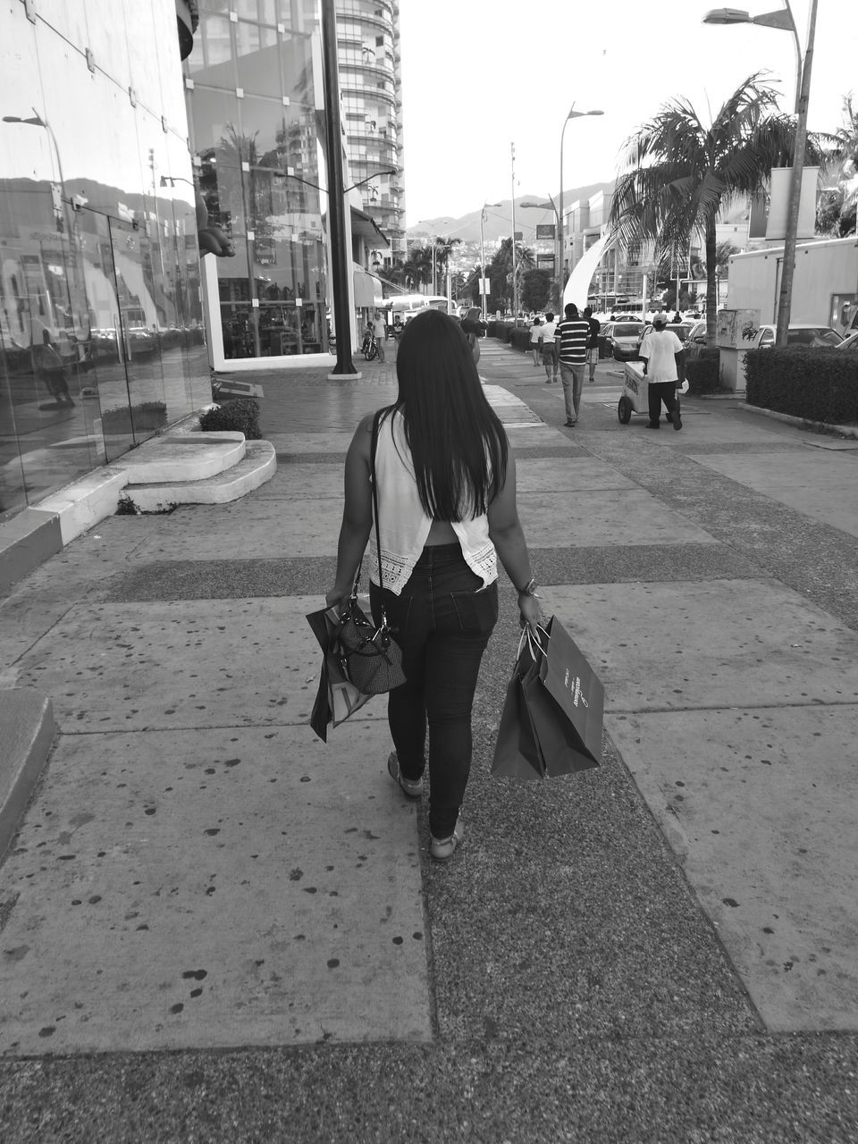 REAR VIEW OF WOMAN WALKING ON STREET