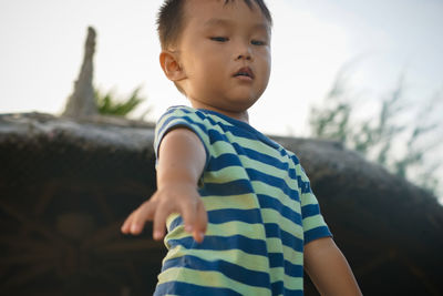 Close-up of boy standing against sky