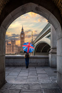 Woman standing against big ben seen through archway