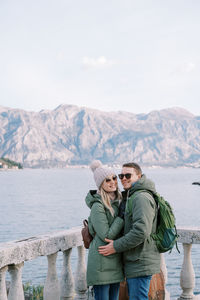 Portrait of senior couple standing against lake
