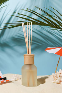 Aroma reed diffuser glass bottle on the sea beach in the summer morning