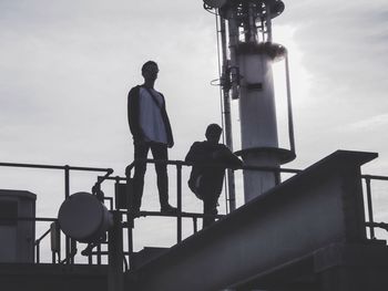 Low angle view of silhouette people standing against sky