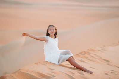 Portrait of young woman sitting on sand at beach