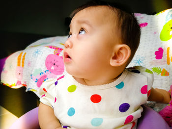 Close-up of cute baby girl on bed