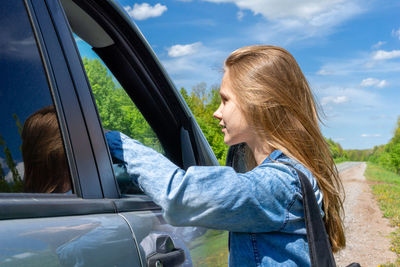 Side view of girl standing by car