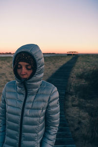 Portrait of woman standing in snow against sky during sunset