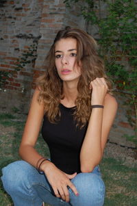 Teenage girl crouching against brick wall