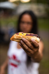 A woman holding and outstretched hotdog.