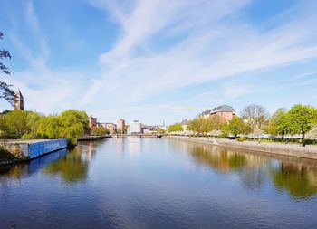 Arch bridge over river amidst buildings against sky