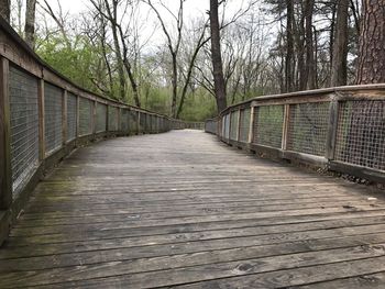 Footbridge over river amidst trees against sky