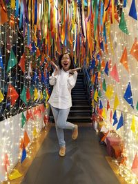 Portrait of surprised woman standing against multi colored illuminated decoration