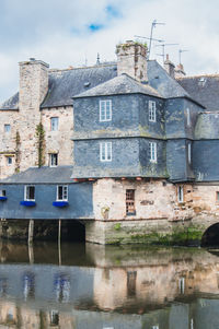 Old building by river against sky