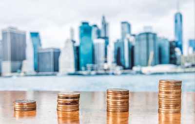 Stack of coins in city against buildings