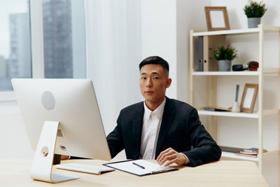Portrait of businessman using laptop at desk in office