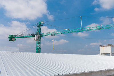 Low angle view of crane at construction site against sky