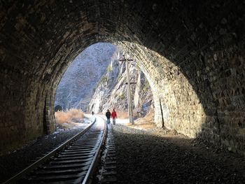 People walking by railroad track in tunnel