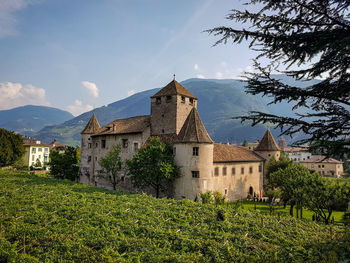 View of mediaeval castle in green field against mountains