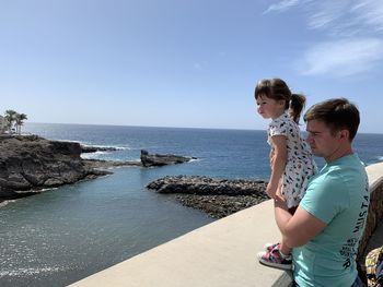 Man with daughter looking at sea