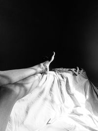 Midsection of person on bed against black background