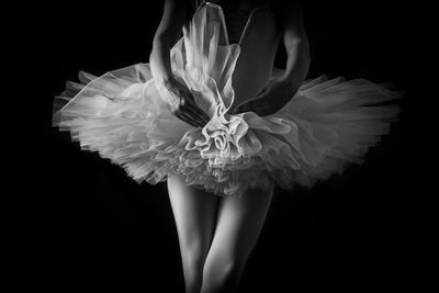 Midsection of ballet dancer against black background