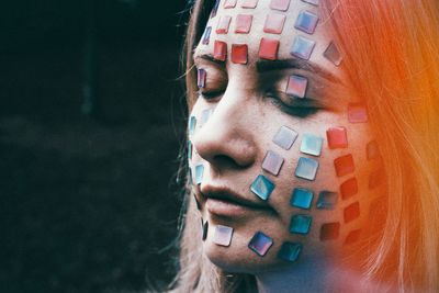 Close-up of woman with eyes closed and decorations on face