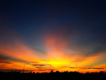 Silhouette trees against dramatic sky during sunset