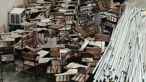 High angle view of abandoned wooden chairs by bamboos