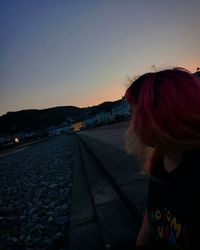 Rear view of woman standing against sky during sunset