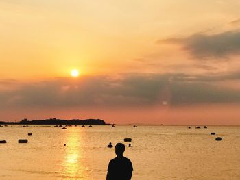 Silhouette people on beach against sky during sunset