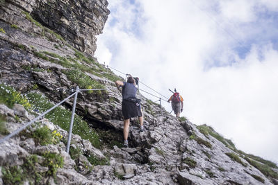 Low angle view of people on rock against sky