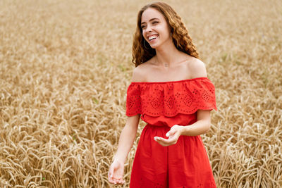  girl, dressed in a red overalls, laughs against the background of a wheat field. emotion concept.