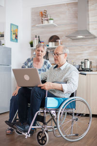 Disabled woman using laptop by man at home