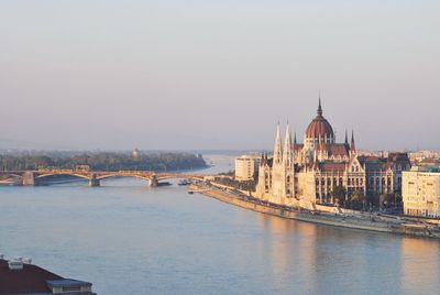 Bridge over river in city against clear sky