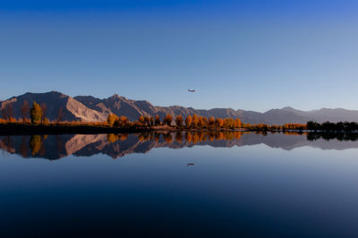 Reflection of mountains in lake against clear blue sky