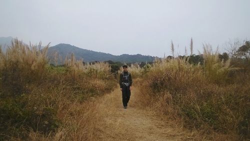 Full length of woman walking on field against sky