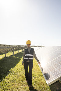 Female maintenance engineer walking near solar panels at power station