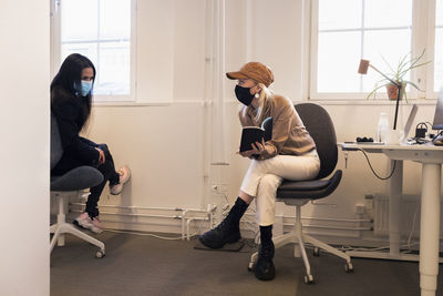 Women in face masks talking in office