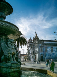 Fountain in front of historical building against sky