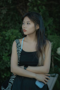 Young woman looking away while standing outdoors