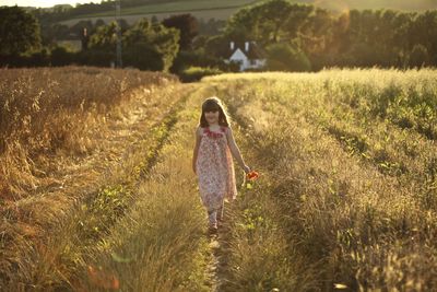 Full length of cute girl walking on sunny field