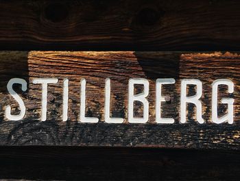 Close-up of text on wooden table against wall