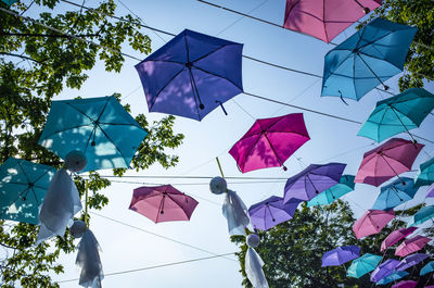 Low angle view of multi colored umbrellas hanging on tree against sky