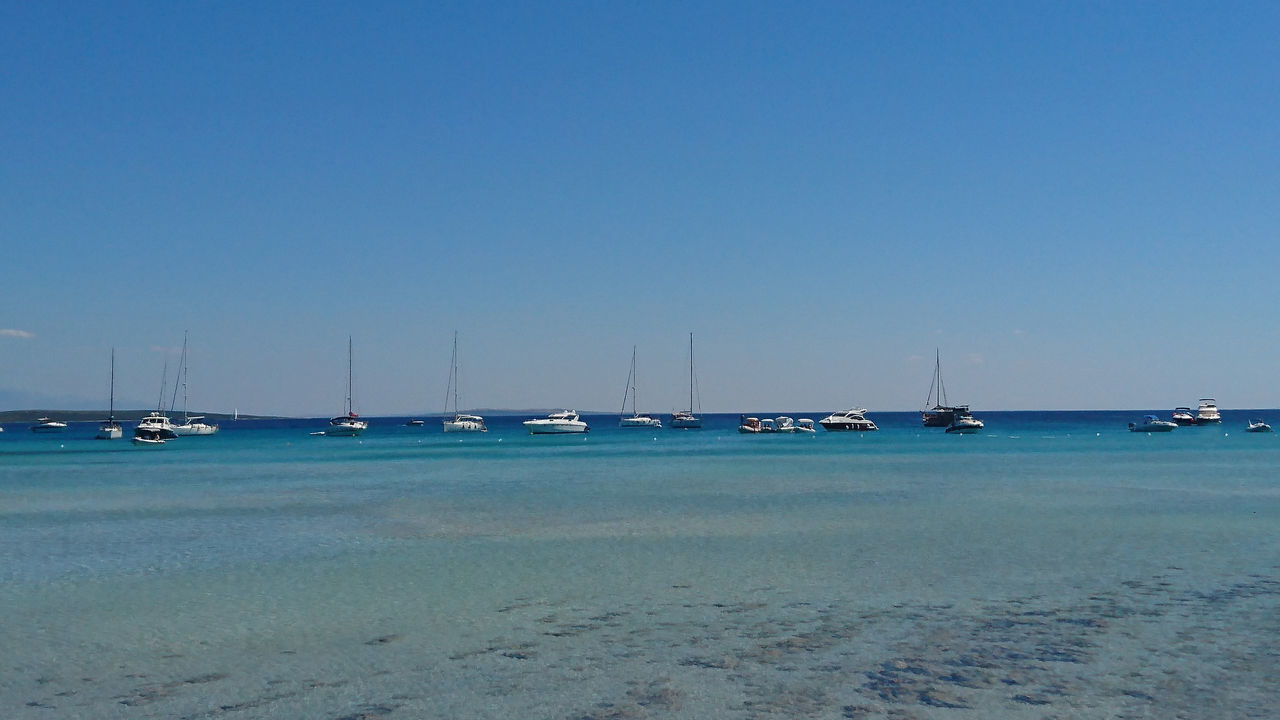 SAILBOATS MOORED ON SEA AGAINST CLEAR SKY