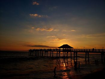 Silhouette pier over sea against sky during sunset