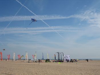 Multi colored kites flying at beach against sky