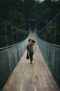 Rear view of boy walking on footbridge