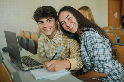 Portrait of happy couple sitting in classroom